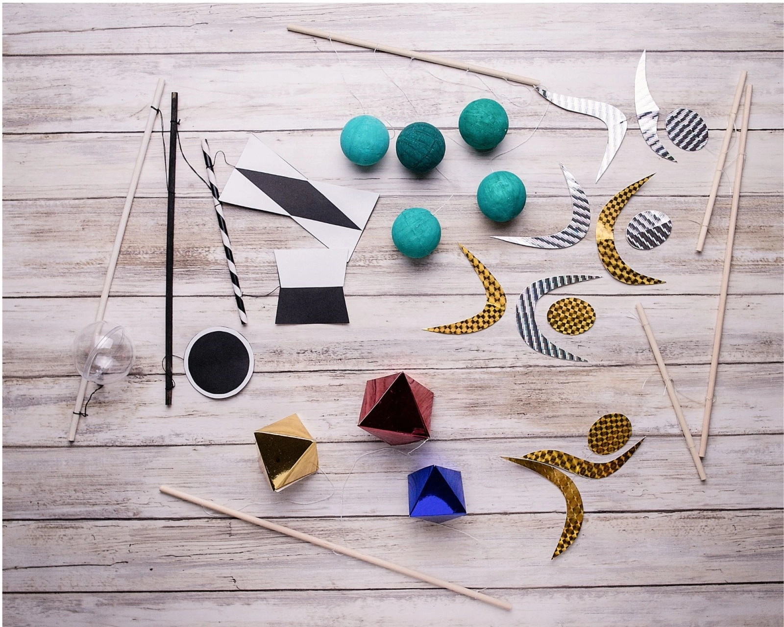 DIY Montessori mobile materials: black and white card shapes, wooden dowels, fishing line and a clear plastic ornament