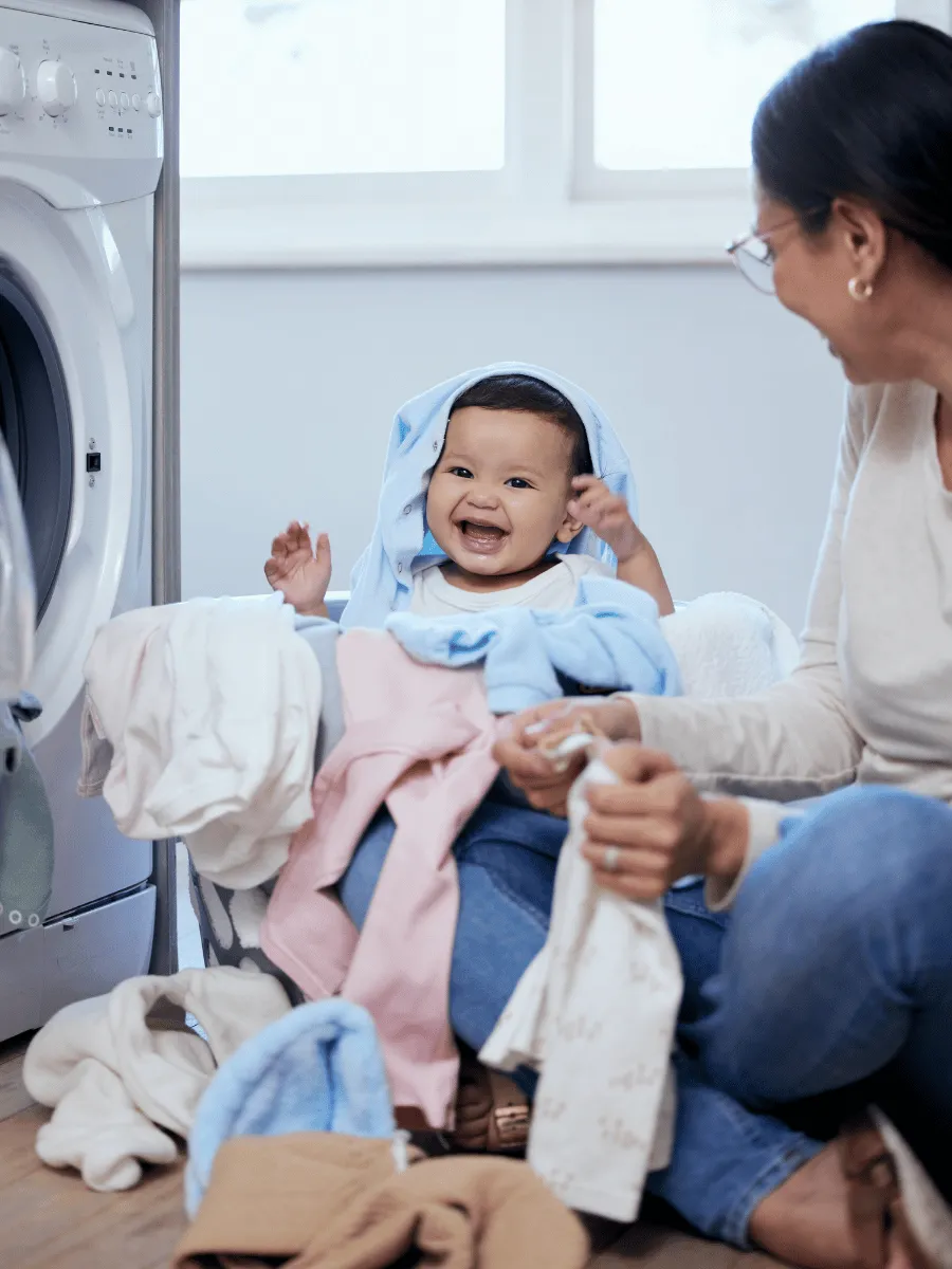 Baby happily played, watching his parents fold clothes a few steps away.