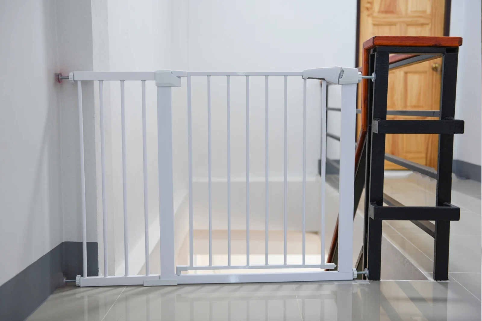 White metal safety gate fitted across the top of a stairway opening