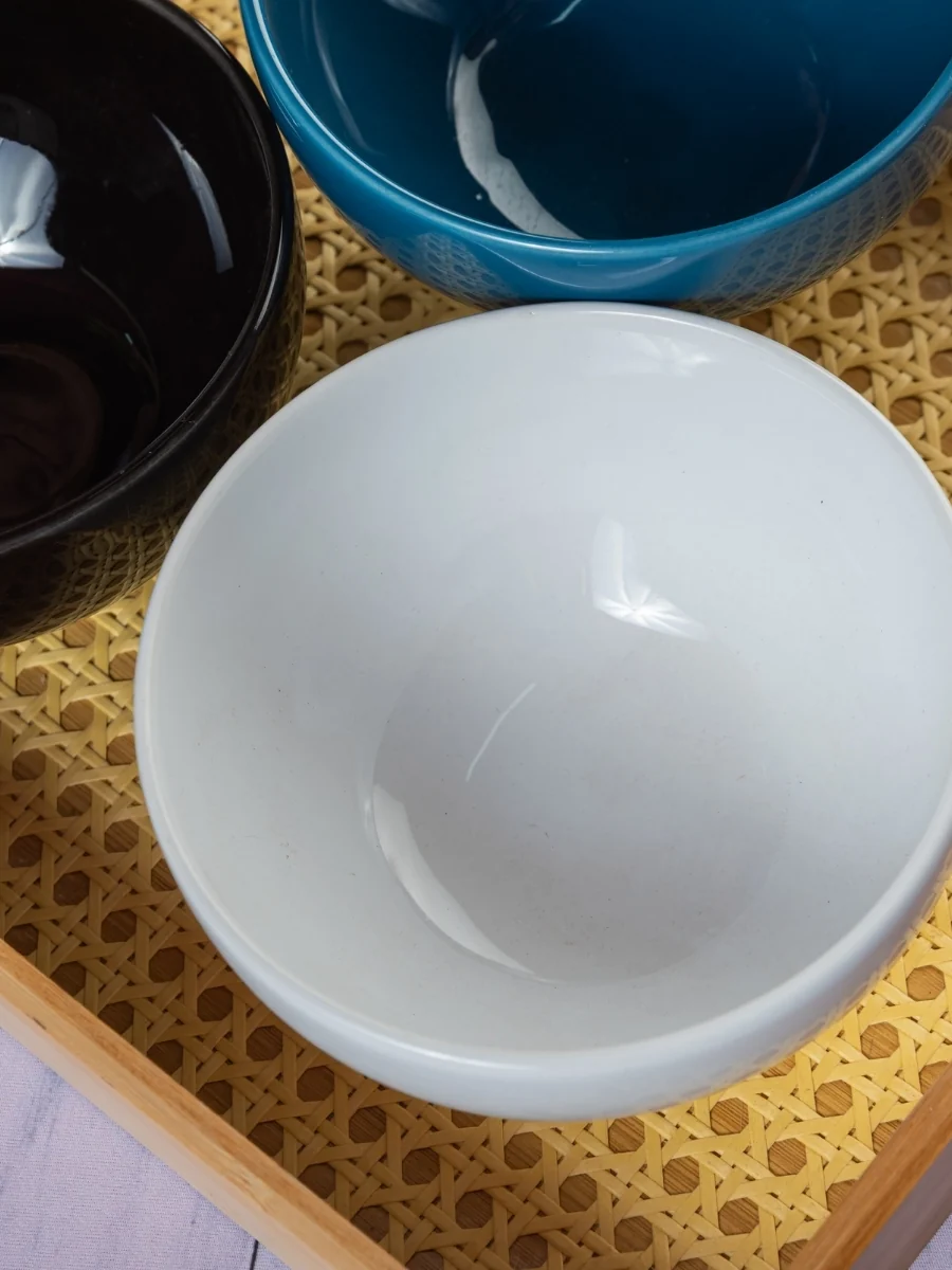 Three ceramic bowls on a bamboo tray with raised edges
