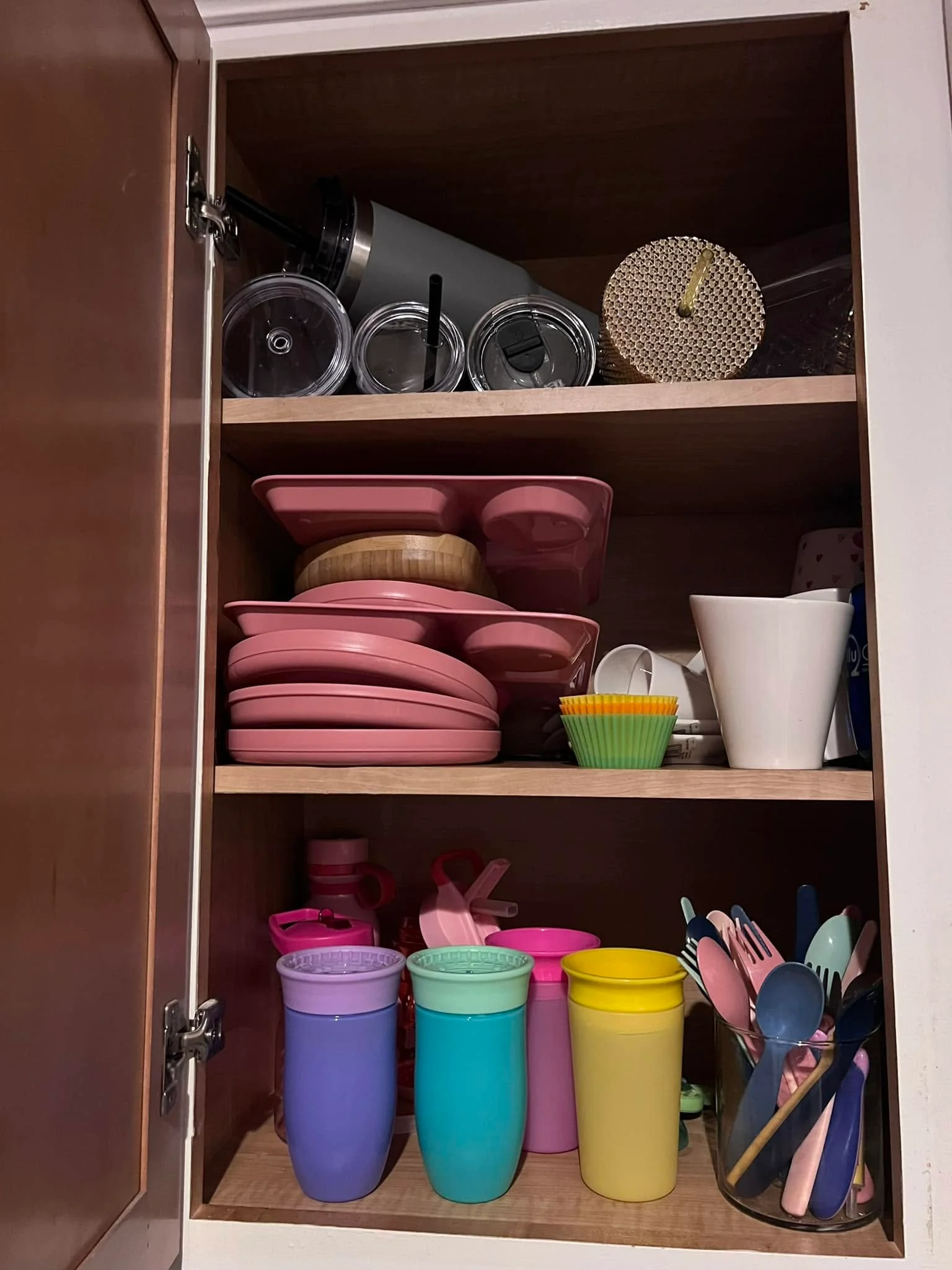 Child-size cups, plates and spoons stacked on a low open kitchen shelf