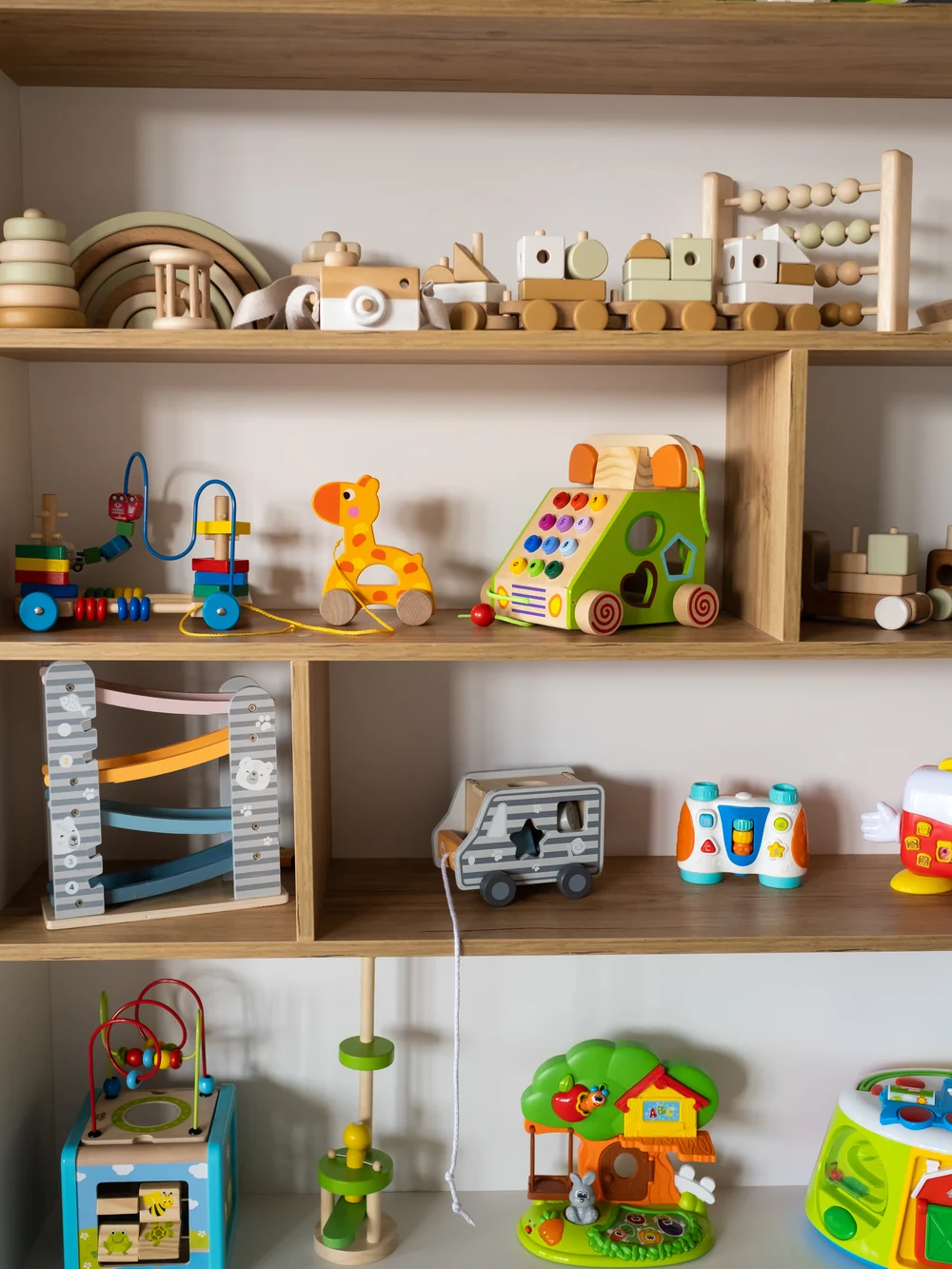 A crowded toy shelf with toys piled on every level