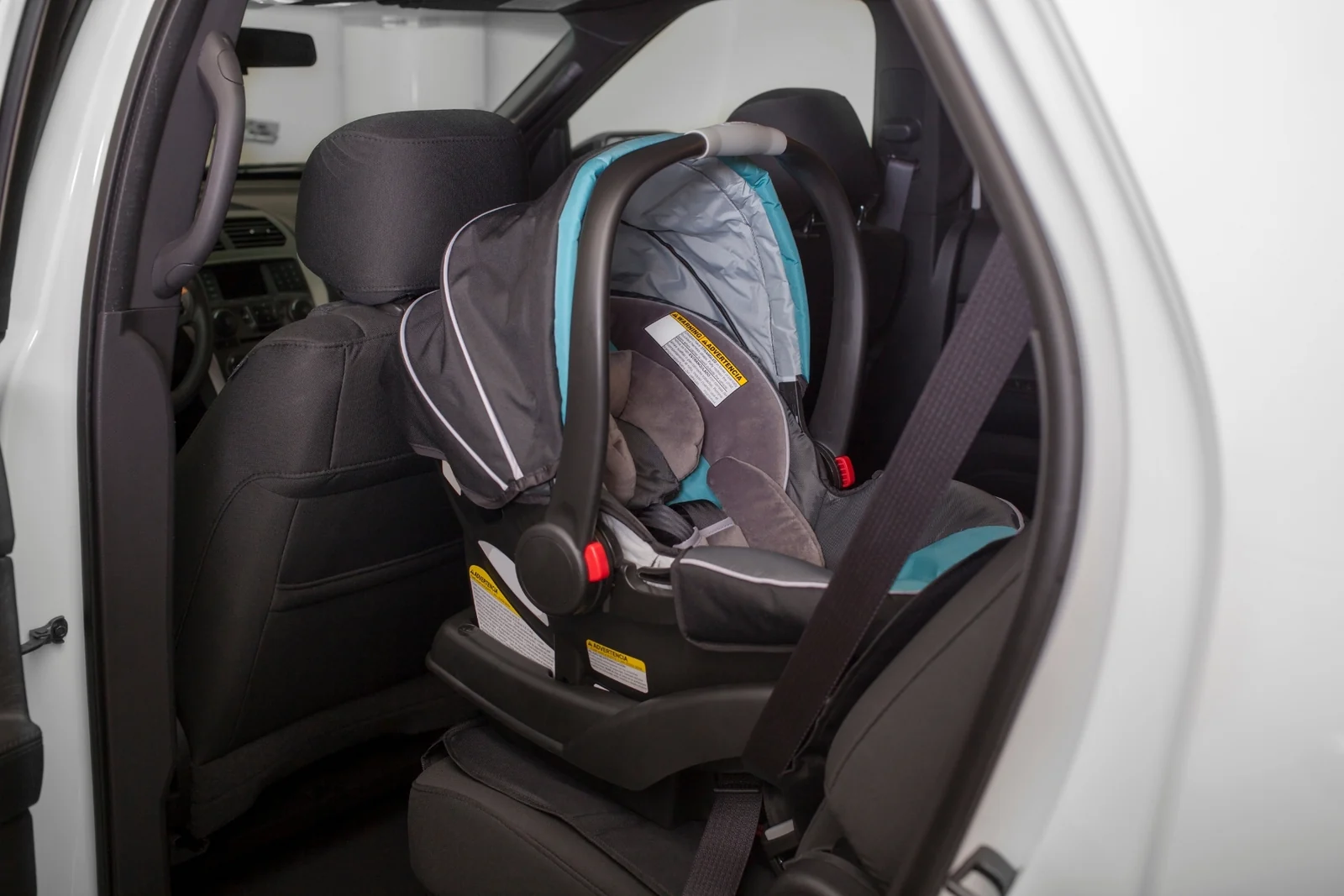 Empty infant car seat on its base in the back seat of a car, nothing clipped to the handle or canopy
