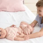 Big brother resting a hand on a newborn lying on a bed: fun activities for siblings to do together