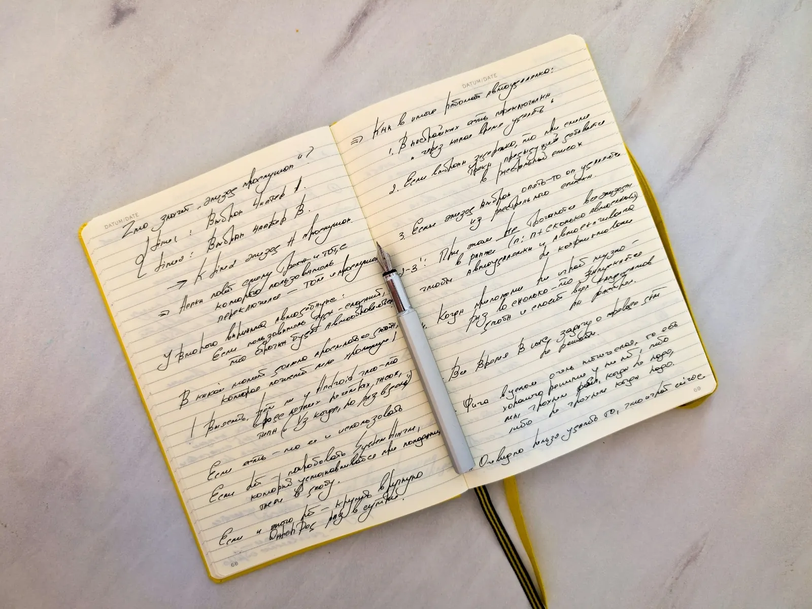 An open notebook filled with handwritten notes, a pen resting across the page