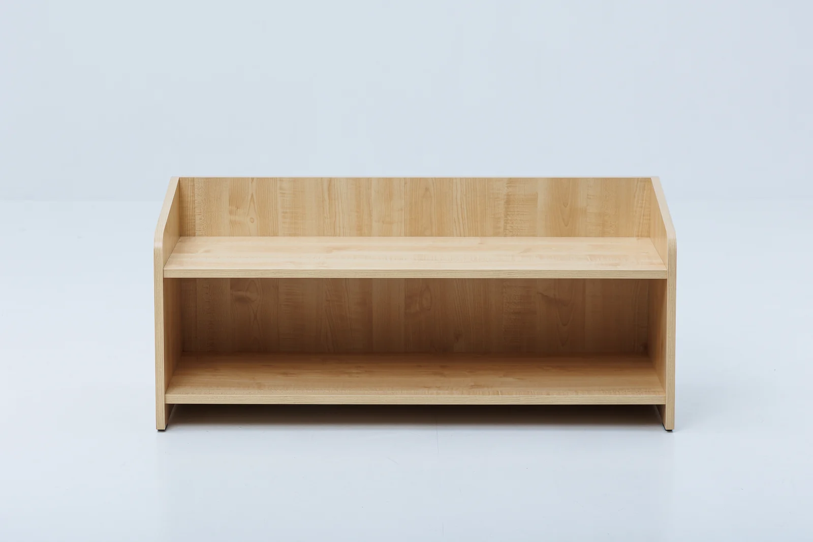 A low, single-level birch plywood toy shelf with a few large wooden toys on it