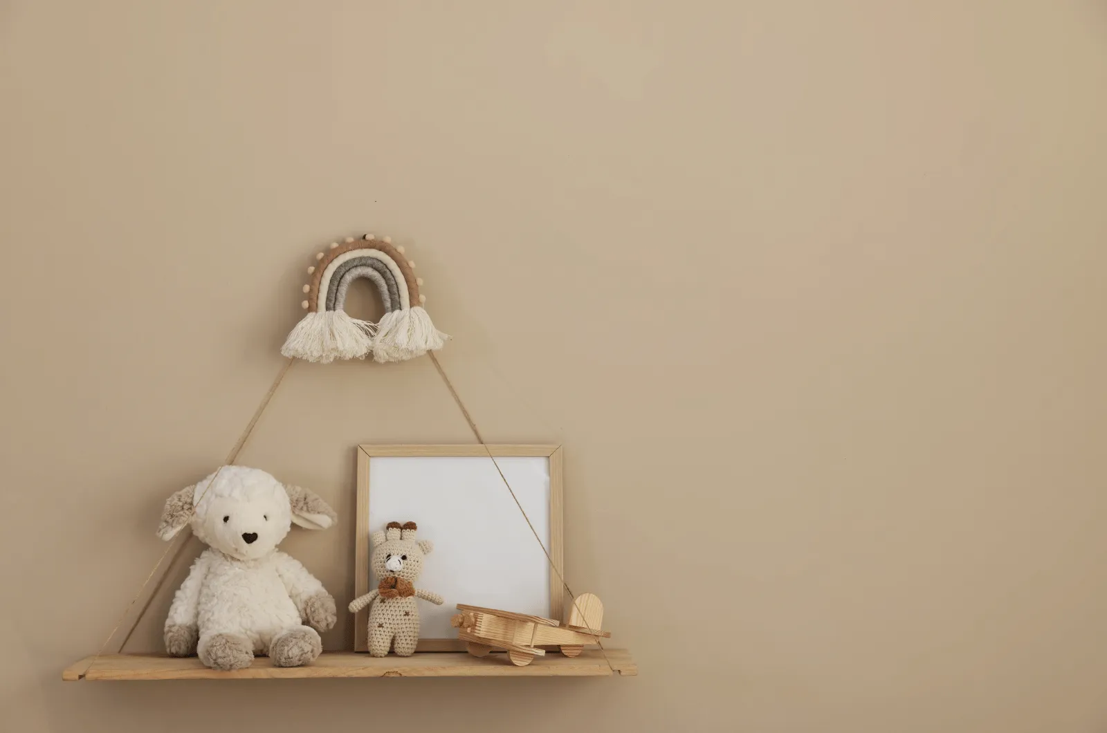 Low wooden toy shelf secured to the wall with a furniture anchor strap