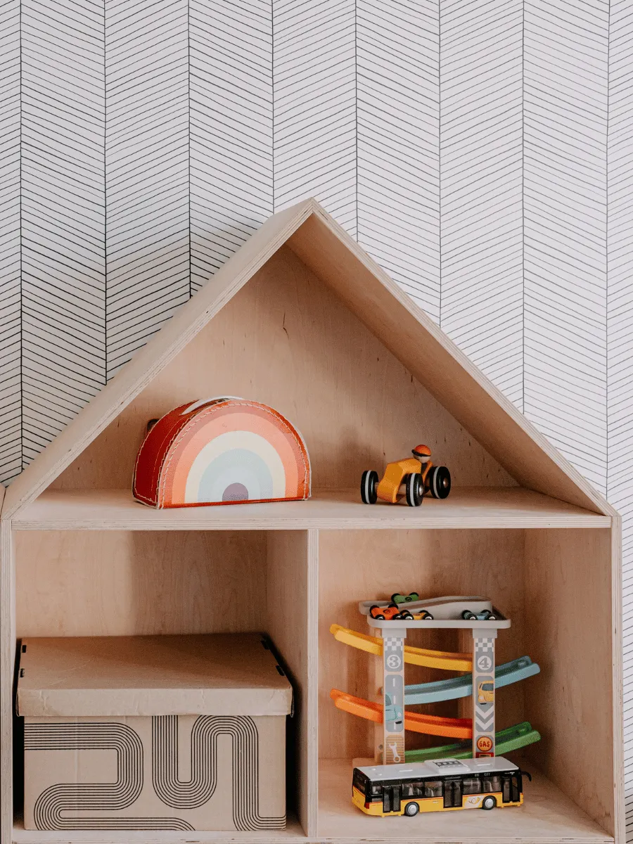 Low wooden Montessori shelf holding four simple toys with space between them