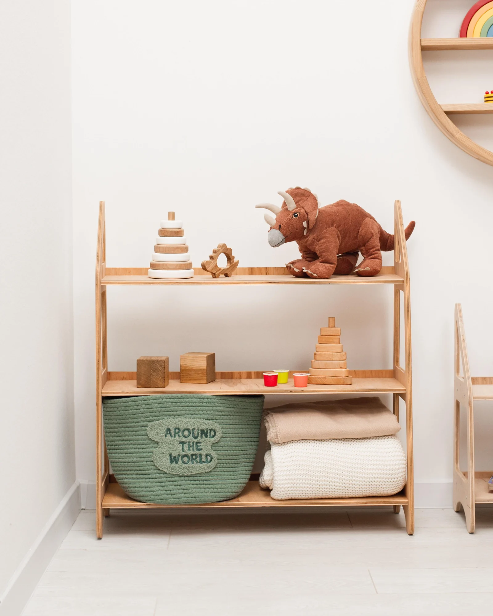 A low open wooden shelf in a living room holds a handful of toys spaced apart
