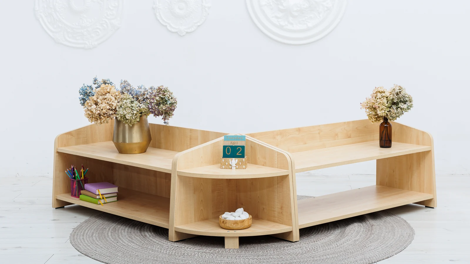 Montessori at home, started small: a low wooden shelf with a few toys and a basket beside a soft rug
