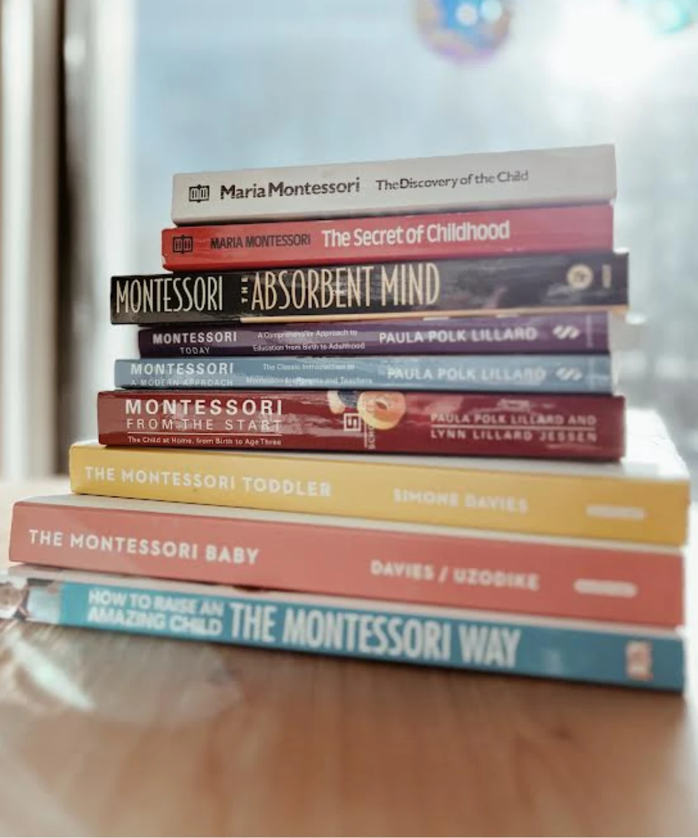 A stack of Montessori and parenting books on a wooden table