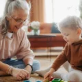 Montessori for grandparents: a grandmother sits on a rug beside her toddler grandchild as he plays with colorful blocks