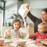 Montessori parenting style in real life: a parent pours flour as a preschooler sifts it and a toddler reaches in to help