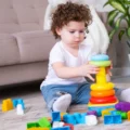 Toddler on a rug, focused on stacking rings onto a stacker, the kind of focus Montessori sensitive periods describe