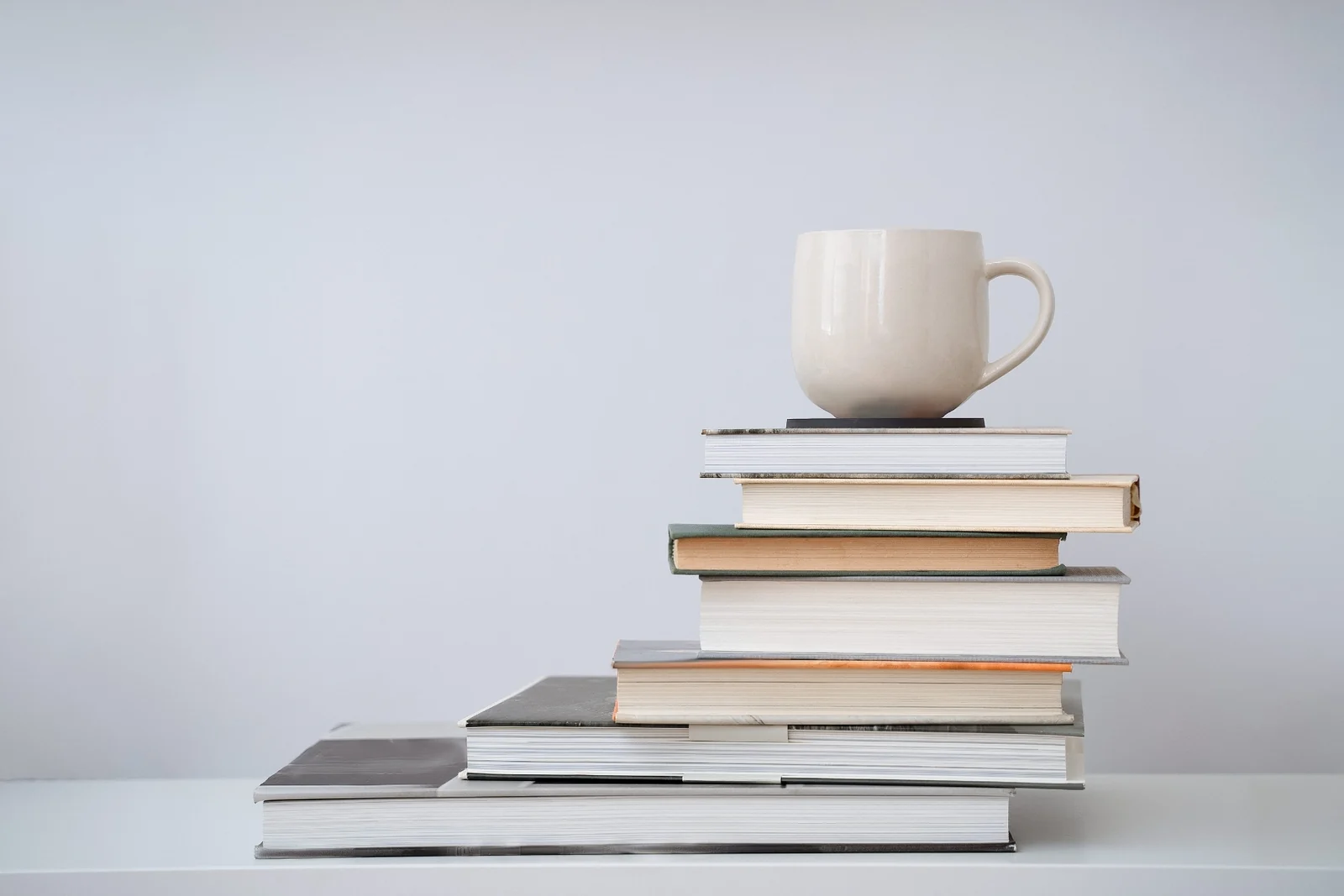 A mug of tea balanced on top of a stack of hardcover books