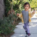 Toddler walking along a sunny neighborhood sidewalk, one of the easiest outdoor activities for toddlers