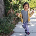 Toddler walking along a sunny neighborhood sidewalk, one of the easiest outdoor activities for toddlers