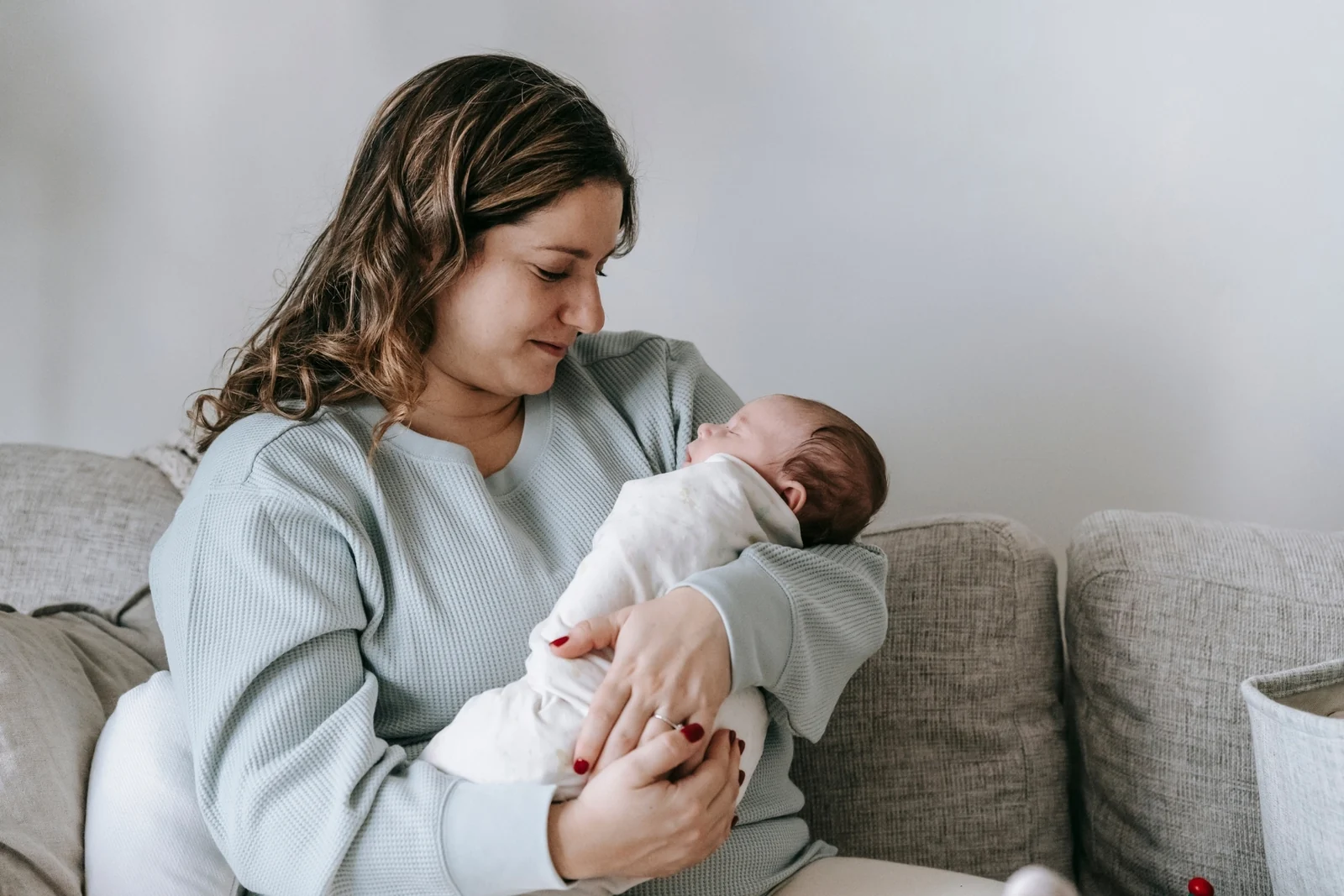 A parent holds a calm baby against their chest in a softly lit living room