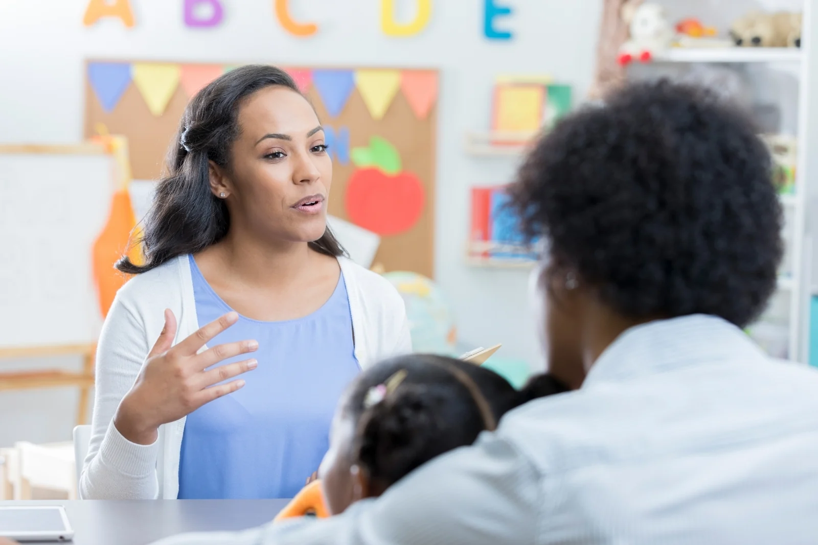 Parent talking with a teacher in a bright preschool classroom