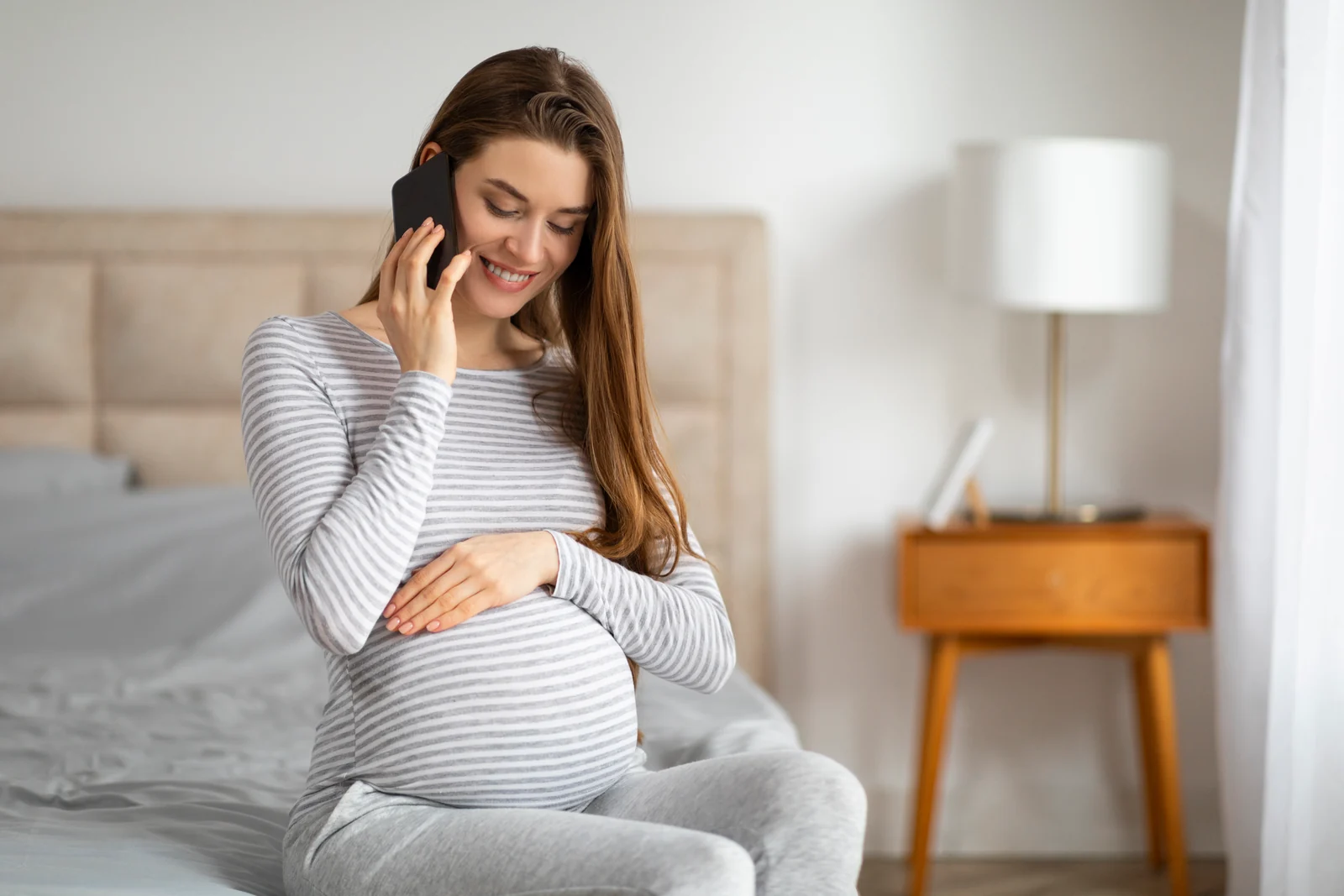 Pregnant person sitting on the floor of a half-finished nursery, looking at a phone