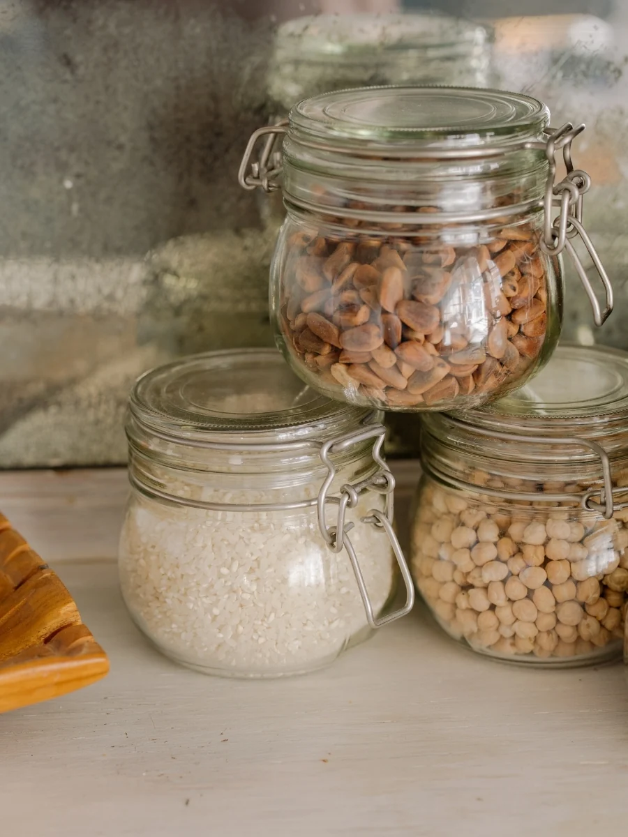 Glass jars of rice, chickpeas and other dried goods on a kitchen shelf