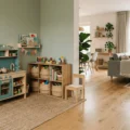 Small playroom design ideas: a play kitchen and a low shelf with baskets on a jute rug in a living room corner