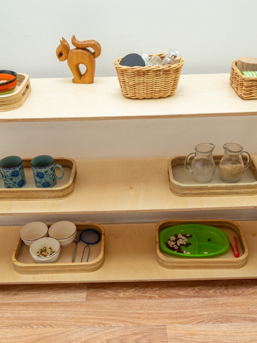 A tidy low shelf with a few toys set out on trays and in baskets