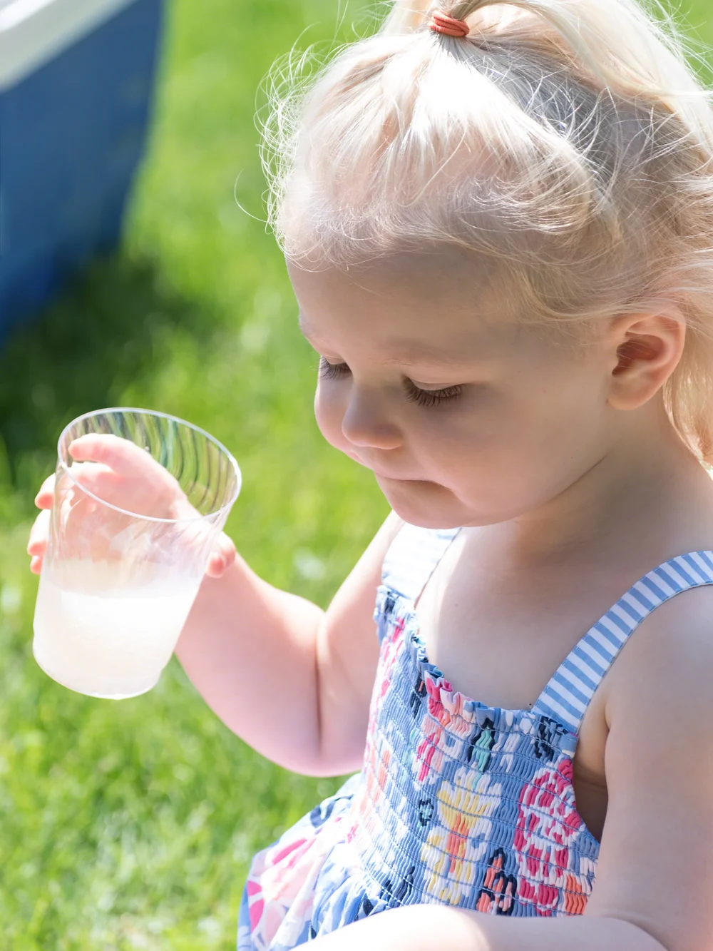 Toddler holding a small cup of water and watching it carefully