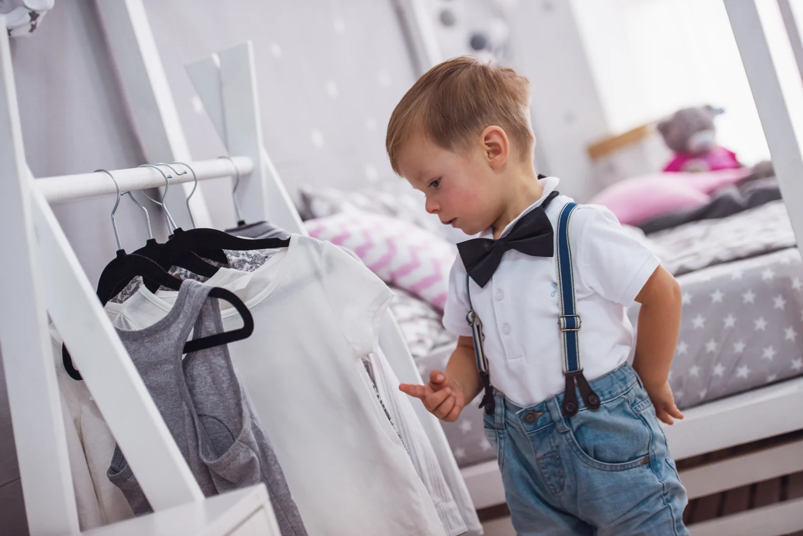 Toddler looking through shirts on a low clothes rack, choosing what to wear