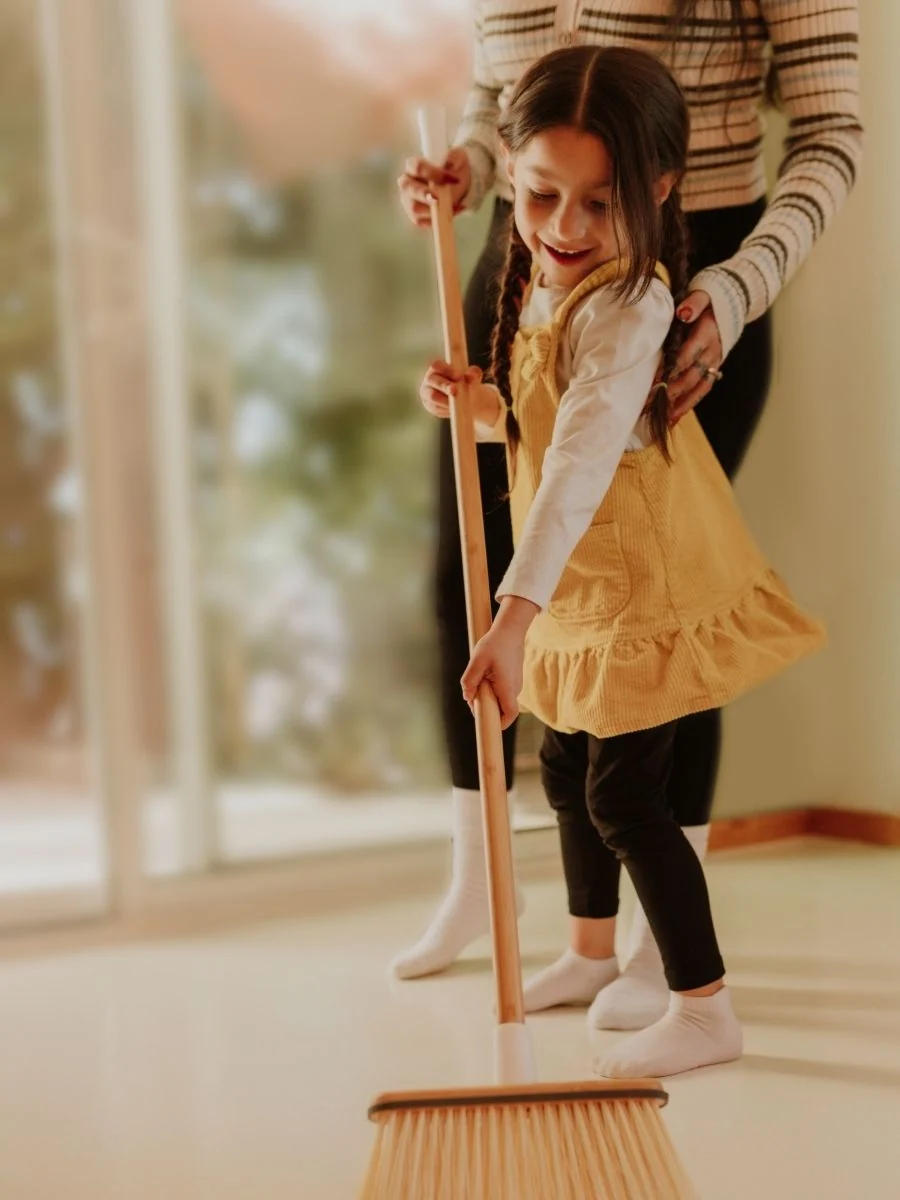 Toddler sweeping the floor with a child-size broom