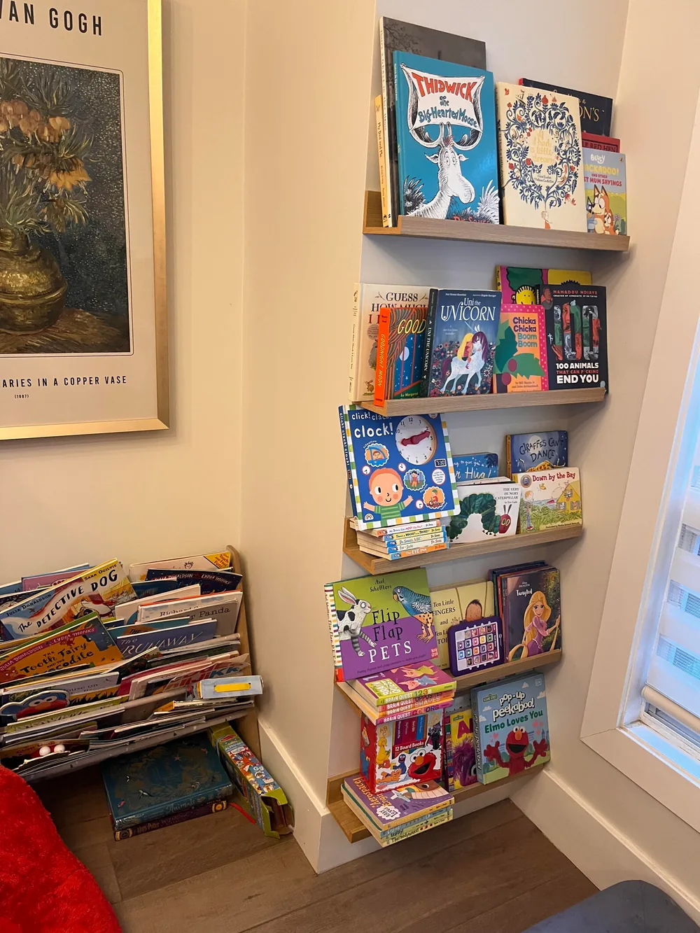 A wall-mounted shelf with picture books standing cover-out in a corner of a room