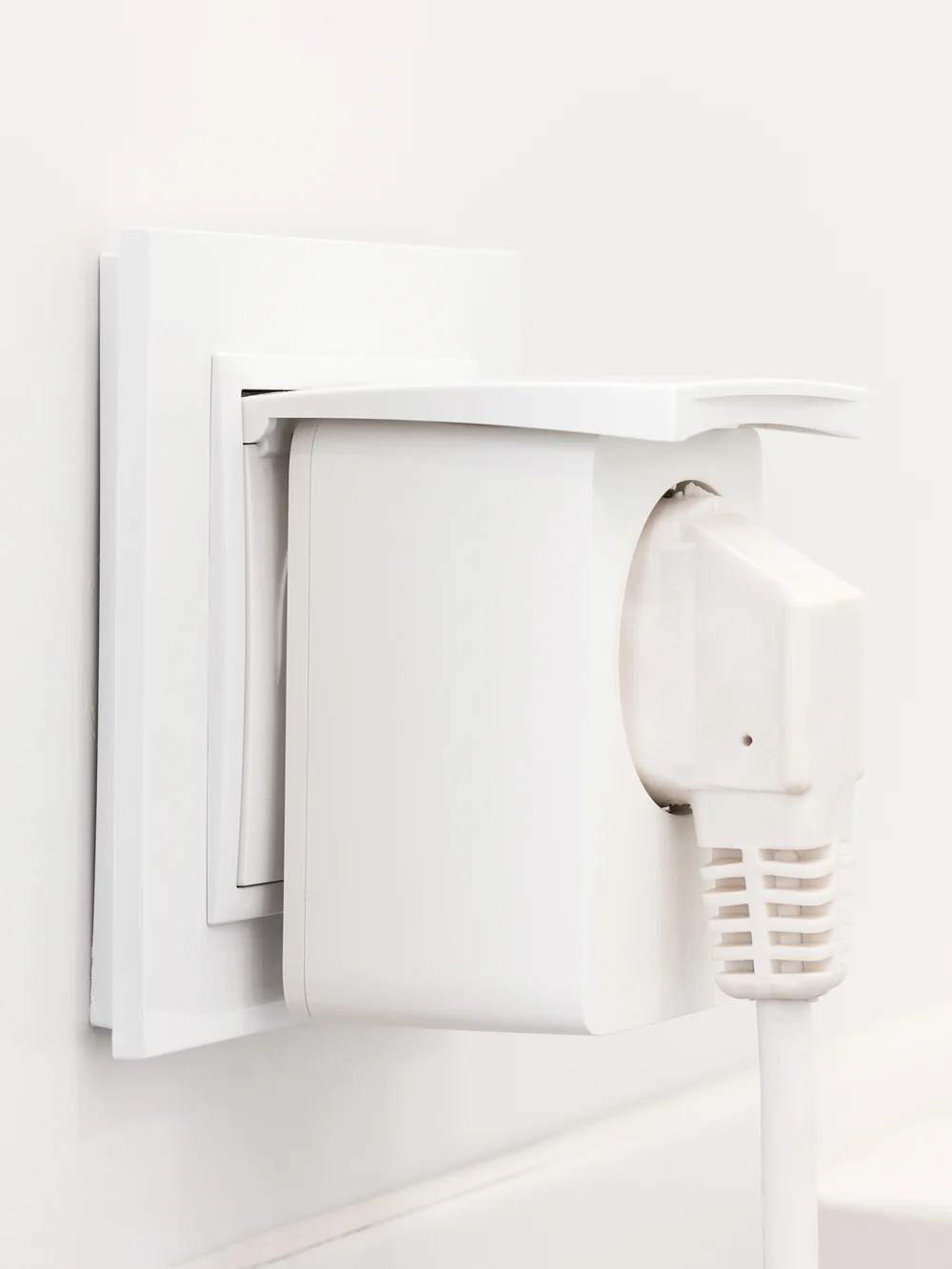 A white wall outlet with a plug connected through a white adapter, the cord hanging down