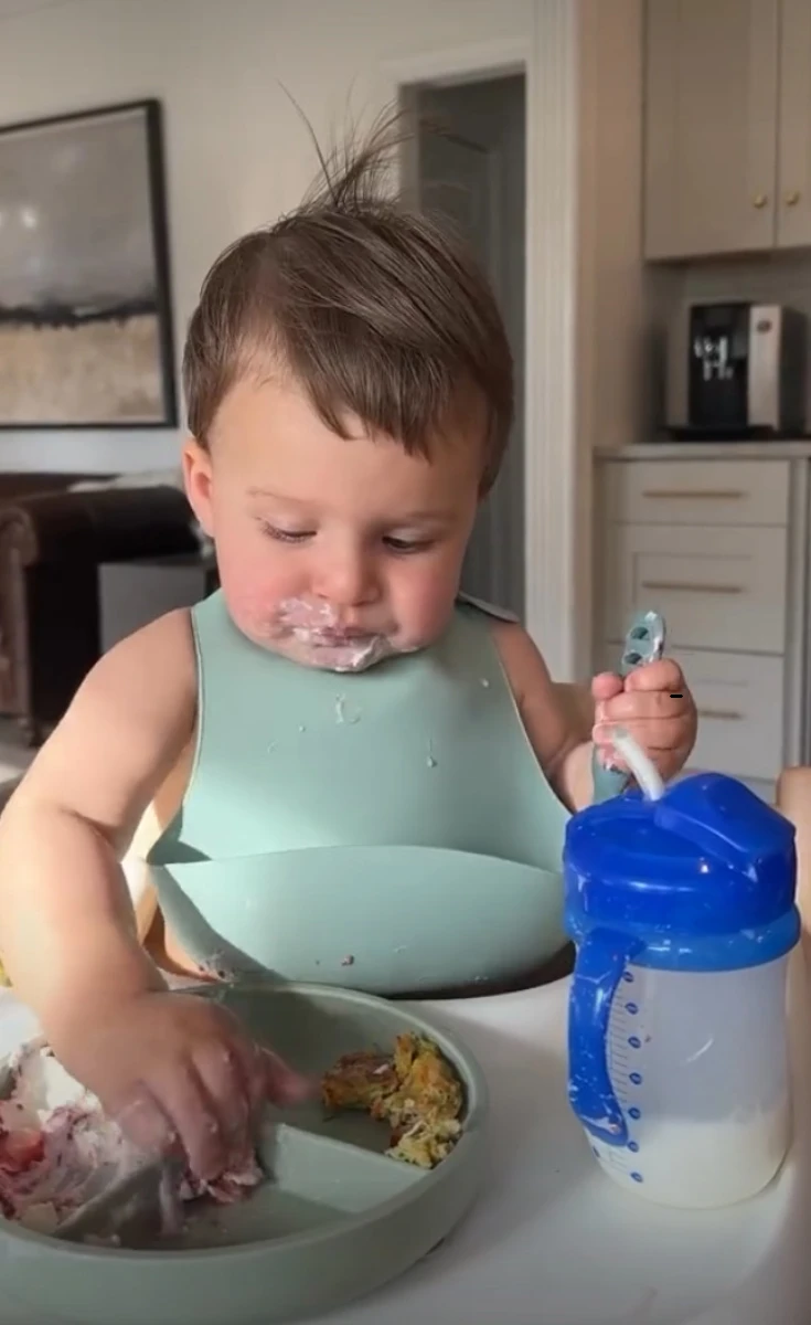 A baby in a high chair feeding himself soft finger foods