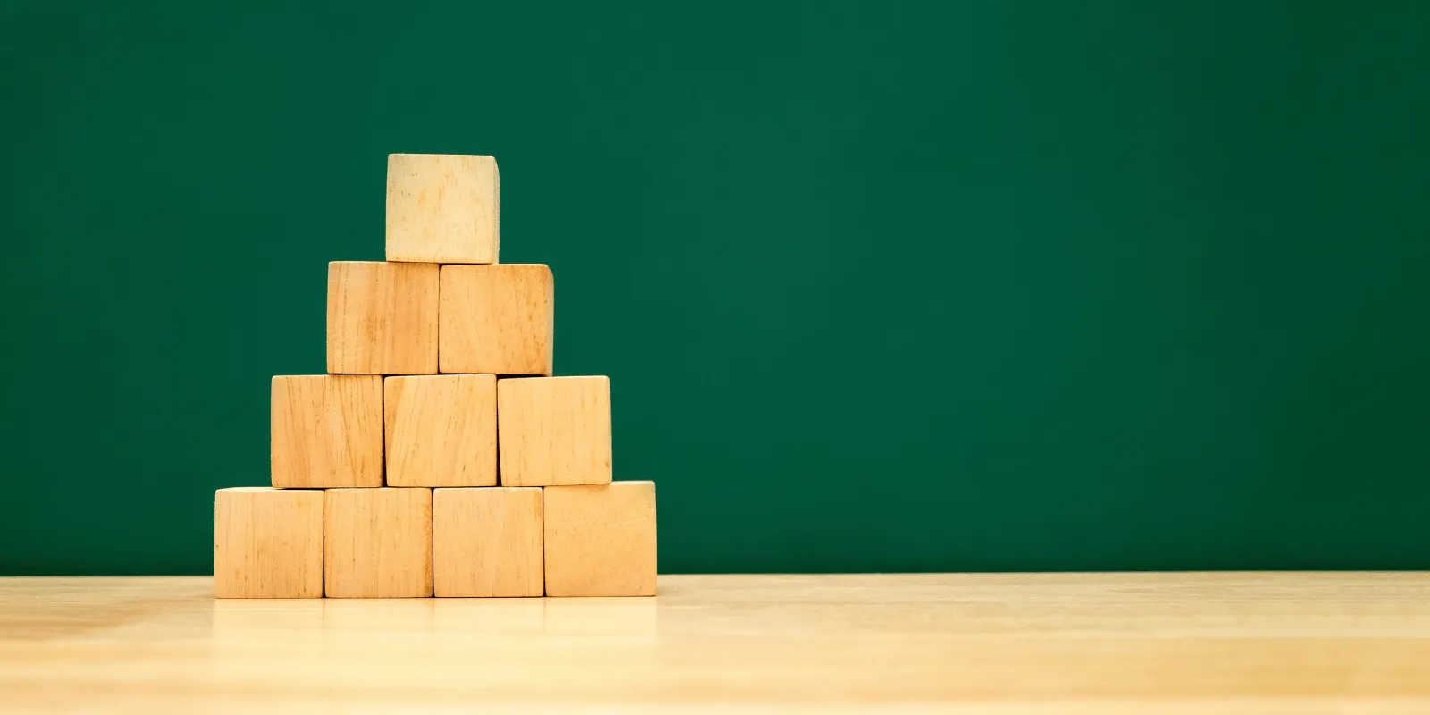 Four plain wooden blocks stacked from largest at the bottom to smallest at the top